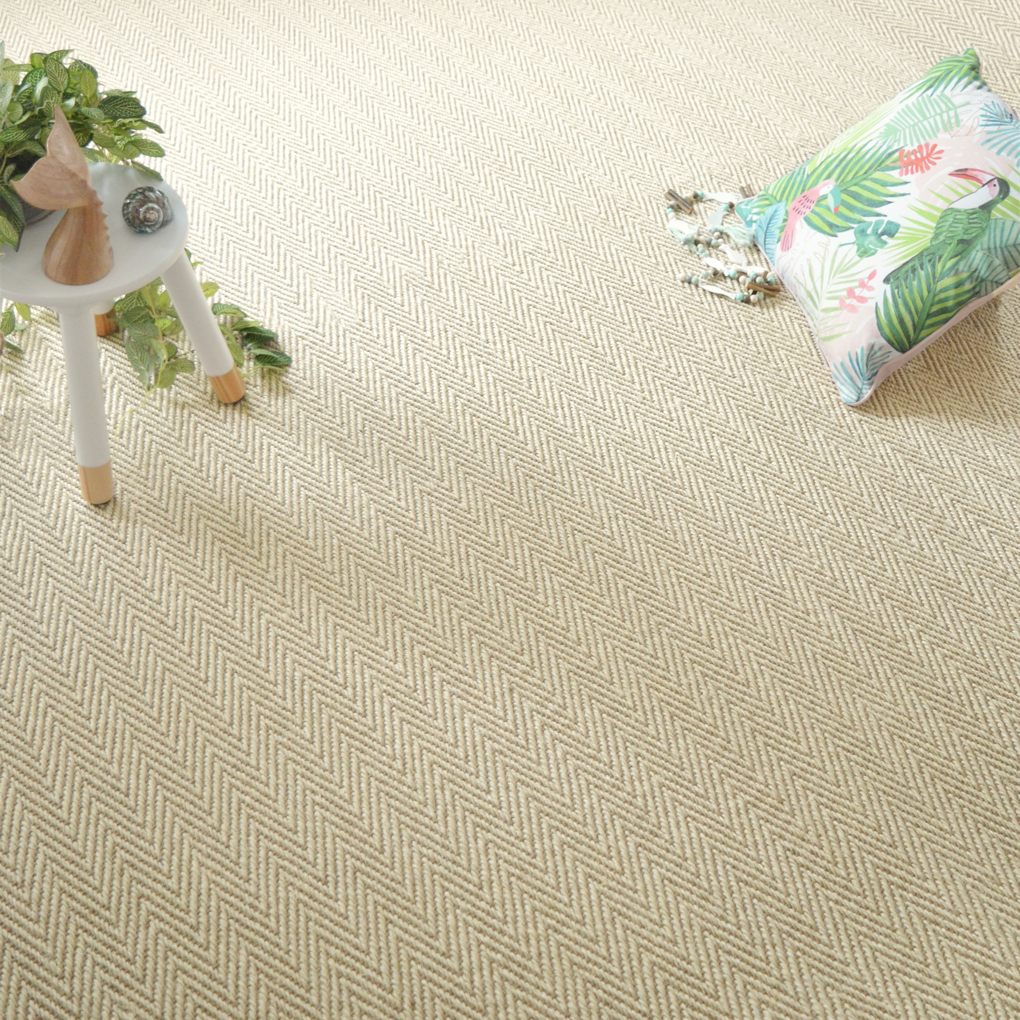 Sol Sisal Chevron - Héritage - Dune avec coussin imprimé feuillage et table blanche dans une ambiance naturelle