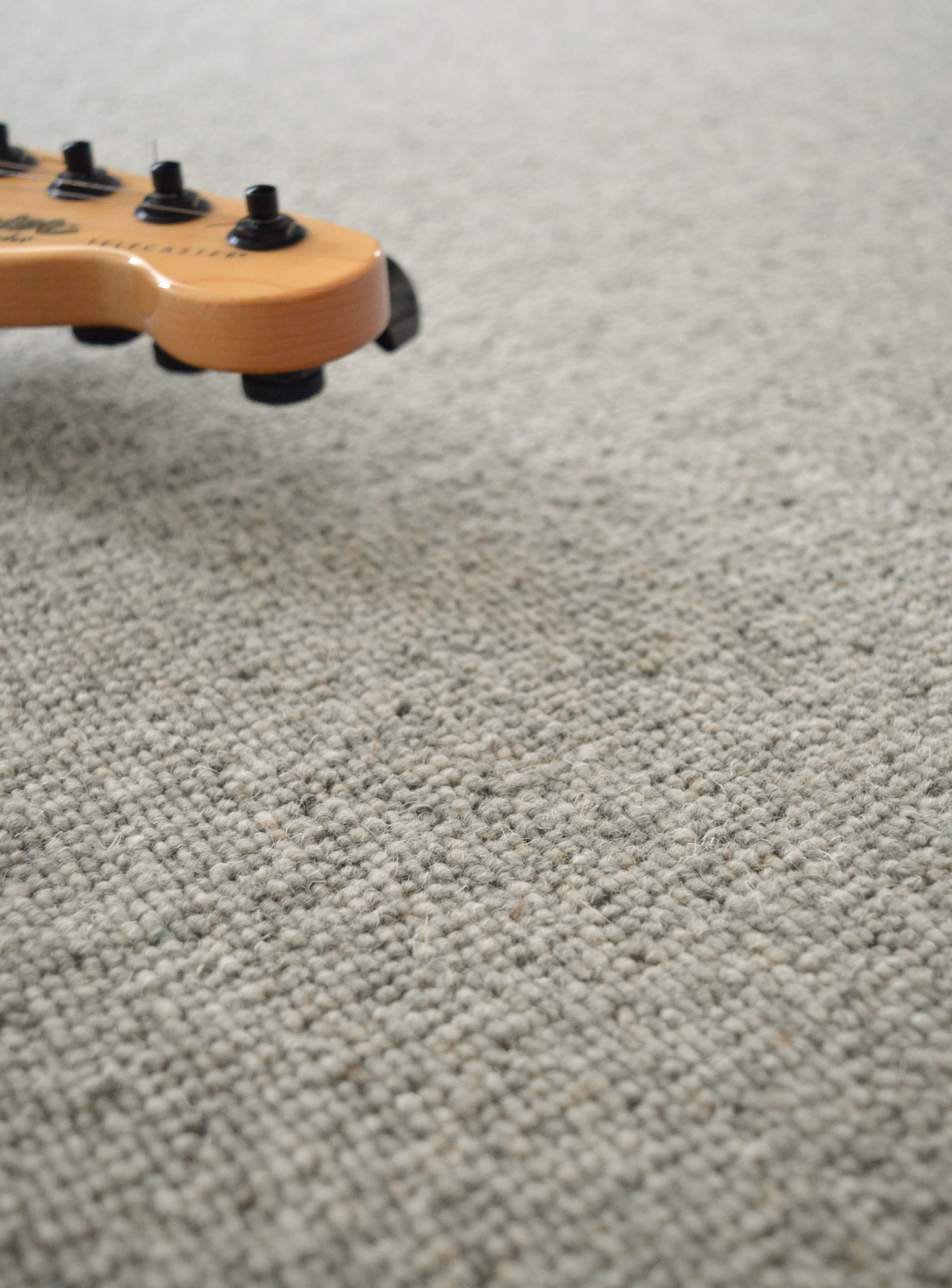 Moquette naturelle en laine - Dolce Vita - Gris nuage avec manche de guitare et texture bouclée apparente