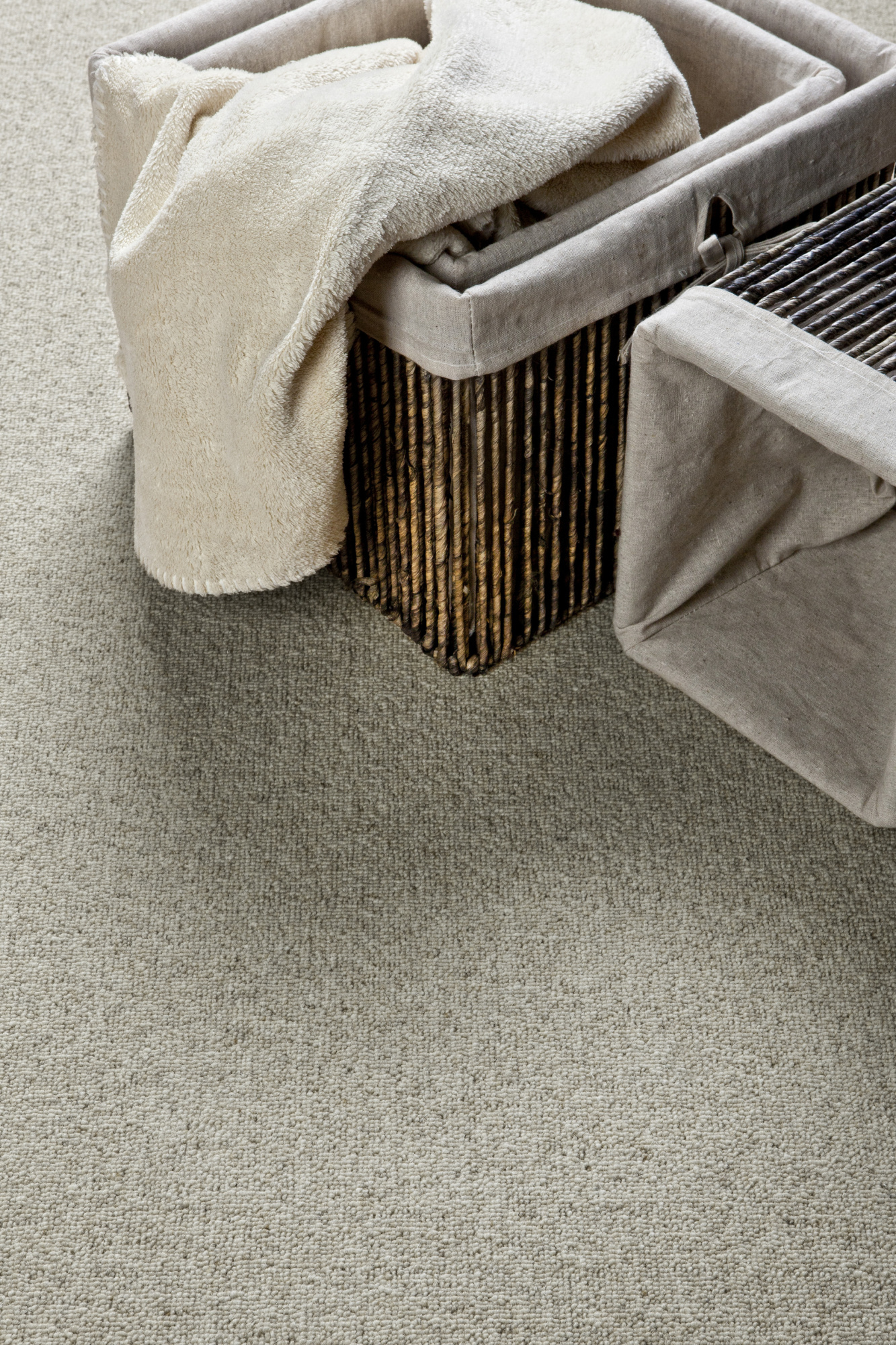 Moquette naturelle en laine Wooly - Gris tendre dans une chambre cocooning avec panier en fibres naturelles et linge clair