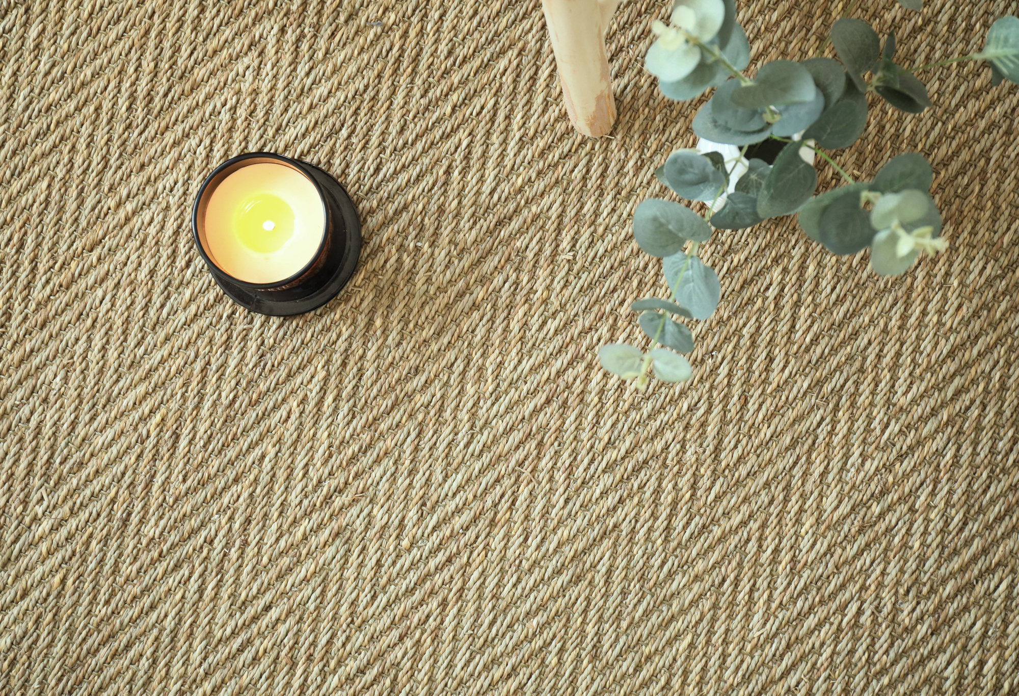 Revêtement de sol Jonc de mer Fin Chevron - Naturel brut dans une ambiance déco naturelle avec bougie et branches d’eucalyptus