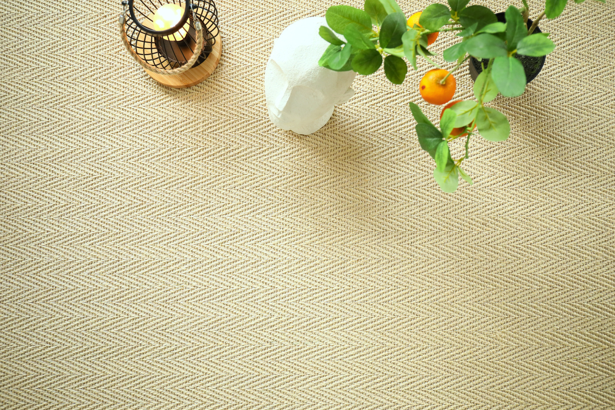 Sol Sisal Chevron - Jazz - Dune accompagné d'une plante fleurie et d'accessoires déco aux tons naturels