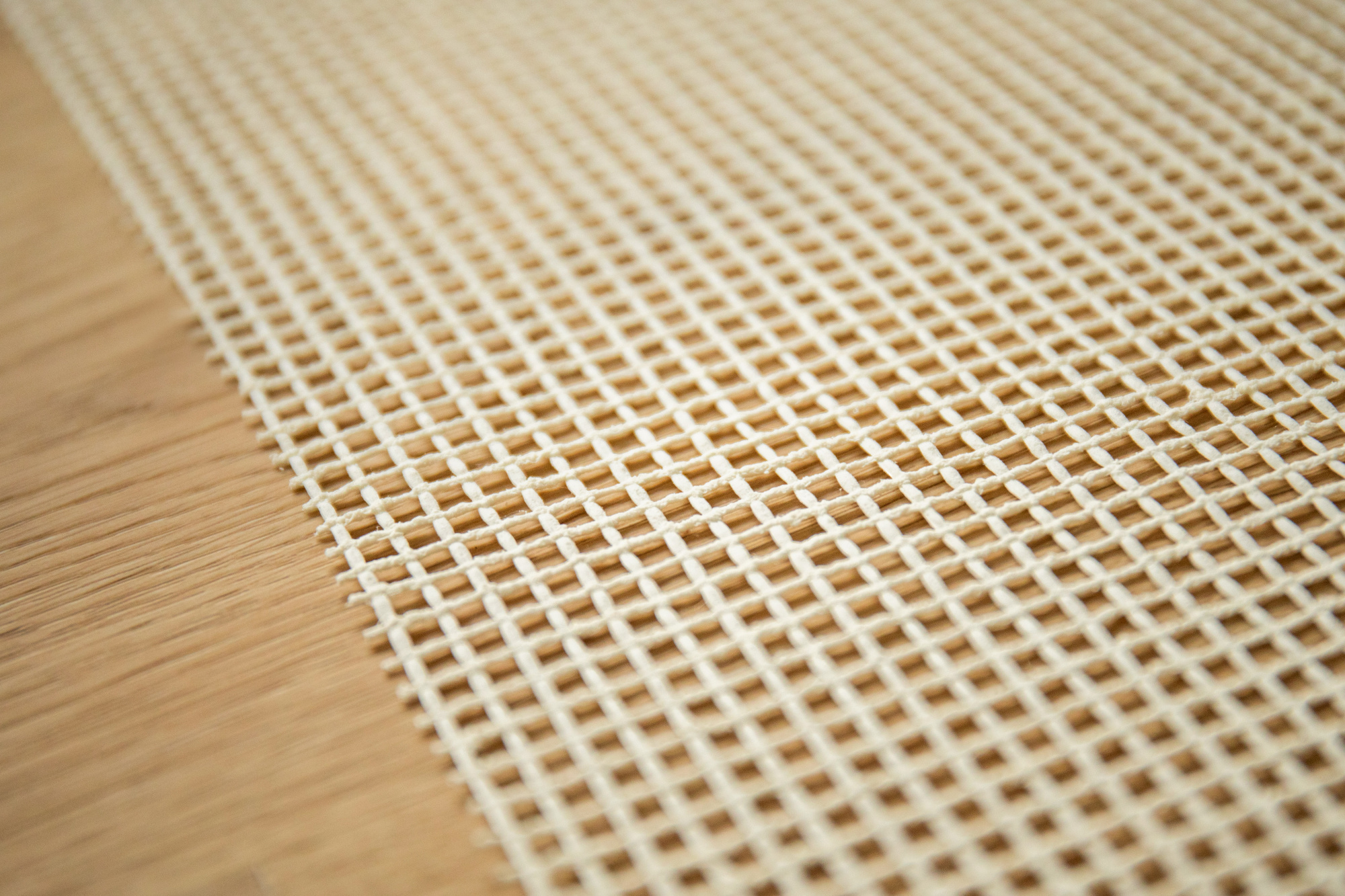 Vue en perspective de la sous-couche antiglisse ACC005 déployée sur parquet avant pose du tapis