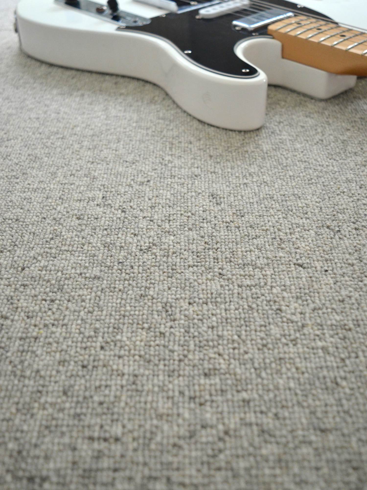 Moquette naturelle en laine - Dolce Vita - Gris nuage avec guitare posée sur un sol en pure laine vierge