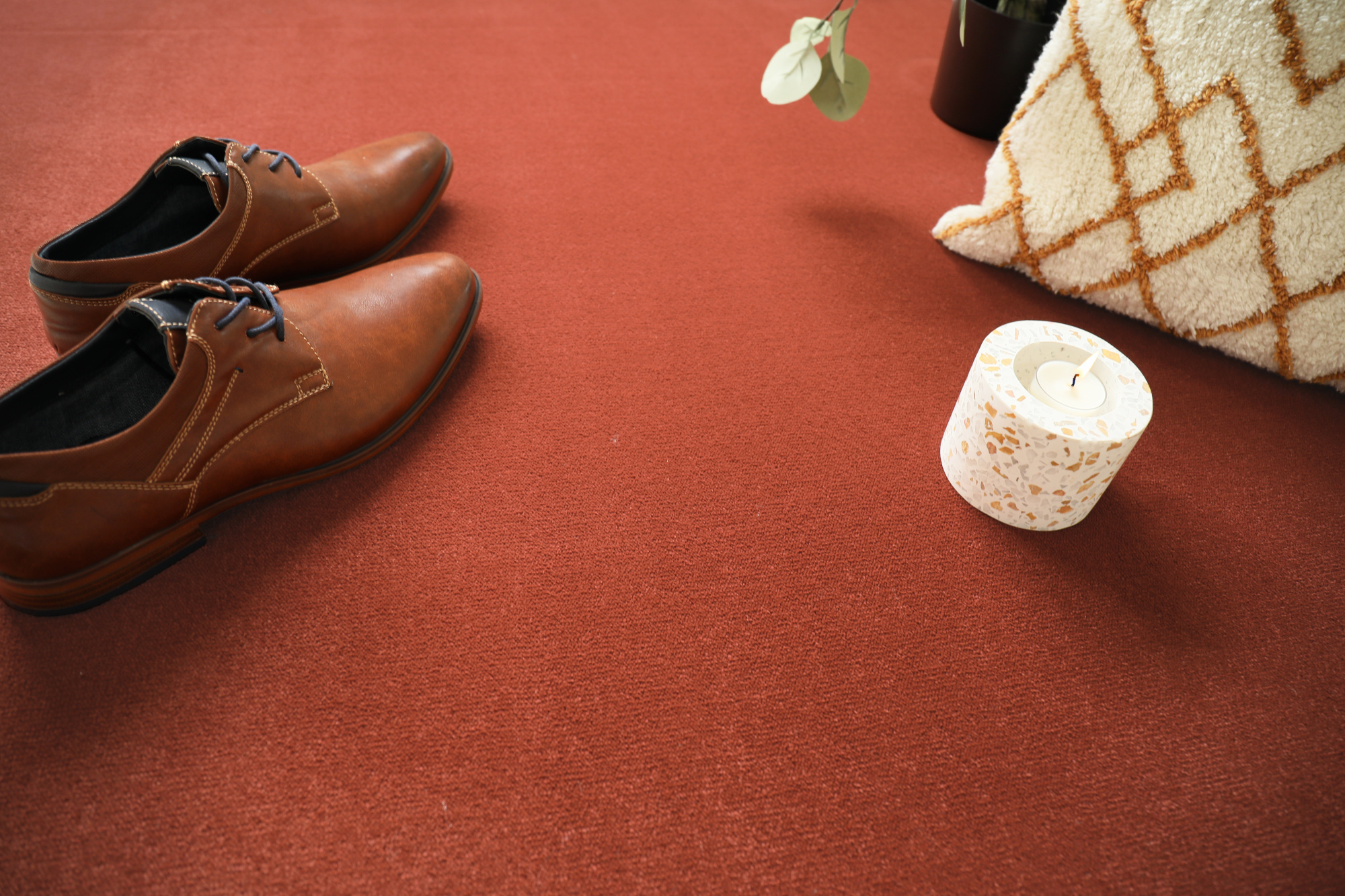 Détail déco sur moquette résistante Sylon rouge tomette et objets de confort