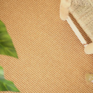 Sol Sisal - Loop - Malt accompagné de grandes feuilles vertes et d'un mobilier en bois naturel