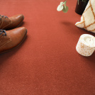 Détail déco sur moquette résistante Sylon rouge tomette et objets de confort