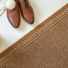Tapis de passage Antidérapant au mètre - Marron associé à des chaussures en cuir sur un sol beige clair